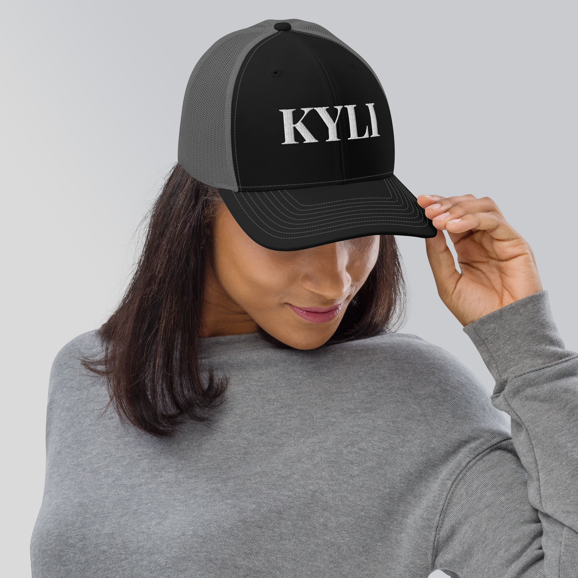 Black and charcoal KYLI trucker cap from the merch collection